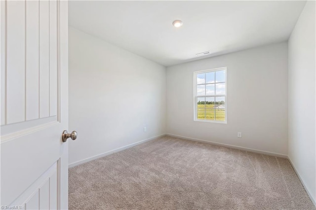 spare room featuring baseboards, visible vents, and light colored carpet