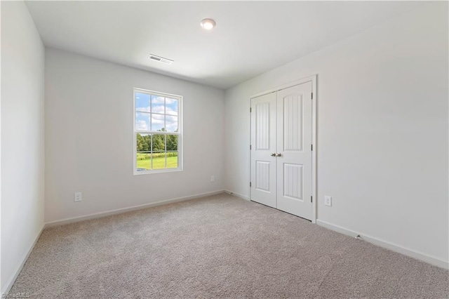 unfurnished bedroom featuring baseboards, visible vents, and light carpet