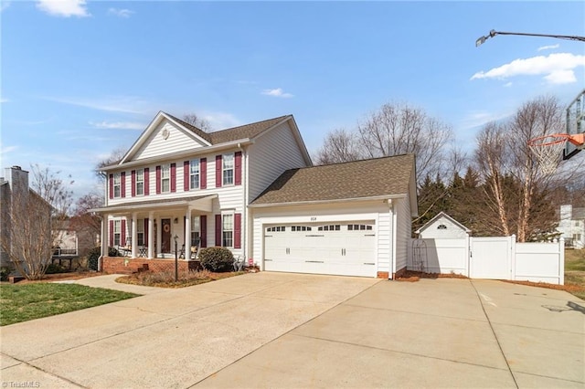 view of front facade featuring driveway, an attached garage, a gate, fence, and a porch