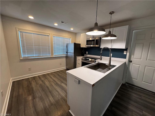 kitchen featuring kitchen peninsula, stainless steel appliances, sink, white cabinets, and hanging light fixtures