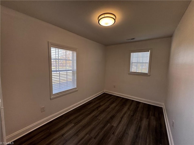 empty room featuring plenty of natural light and dark hardwood / wood-style floors