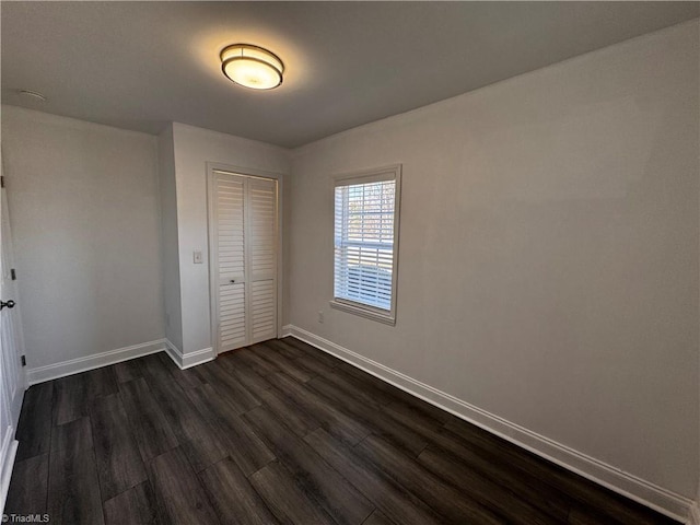 unfurnished bedroom with dark hardwood / wood-style floors and a closet