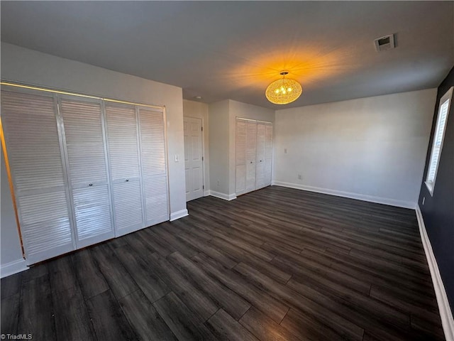 unfurnished bedroom with dark hardwood / wood-style flooring and a chandelier