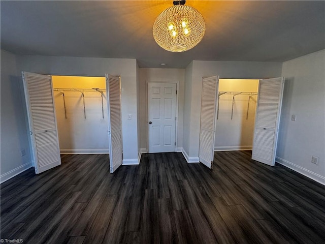 unfurnished bedroom with multiple closets and dark wood-type flooring