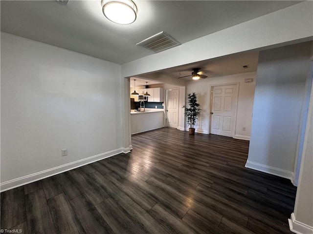 unfurnished living room featuring ceiling fan, sink, and dark wood-type flooring