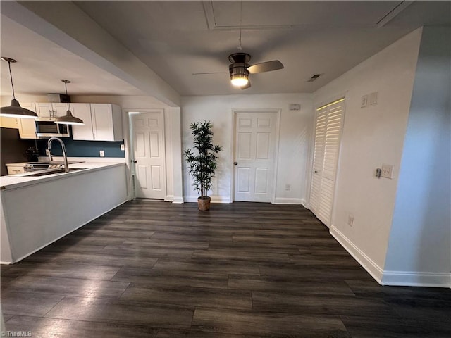 kitchen featuring dark hardwood / wood-style flooring, ceiling fan, sink, white cabinetry, and hanging light fixtures