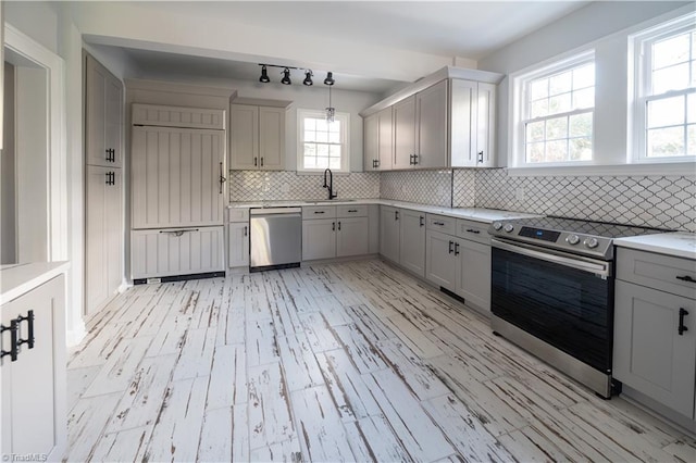 kitchen with decorative backsplash, appliances with stainless steel finishes, a wealth of natural light, and pendant lighting