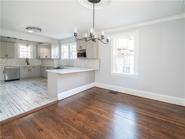 kitchen with tasteful backsplash, kitchen peninsula, stainless steel appliances, and dark wood-type flooring