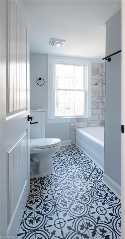 bathroom with a bathing tub, tile patterned flooring, and toilet