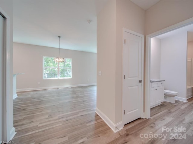 hall featuring an inviting chandelier and light hardwood / wood-style flooring