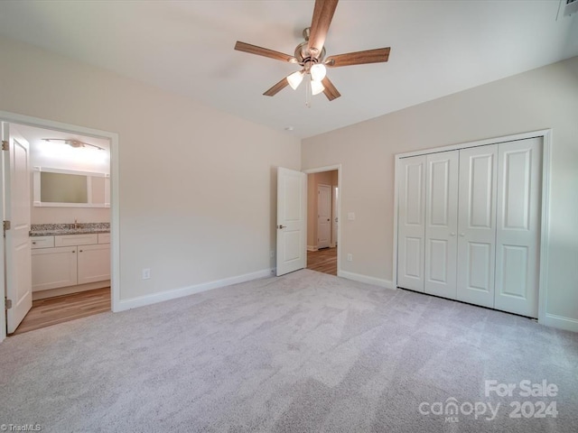 unfurnished bedroom with ensuite bath, ceiling fan, a closet, and light carpet