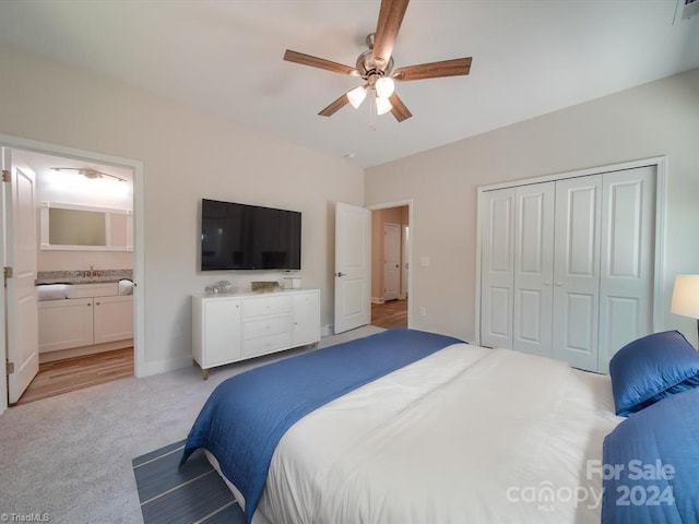 bedroom with ceiling fan, light colored carpet, ensuite bath, and a closet