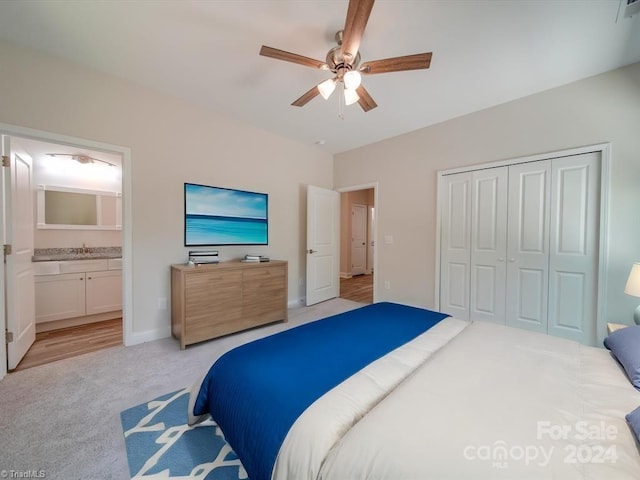 carpeted bedroom featuring ceiling fan, sink, ensuite bathroom, and a closet