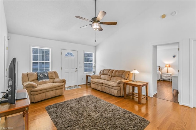 living area with baseboards, light wood-style flooring, high vaulted ceiling, and a ceiling fan