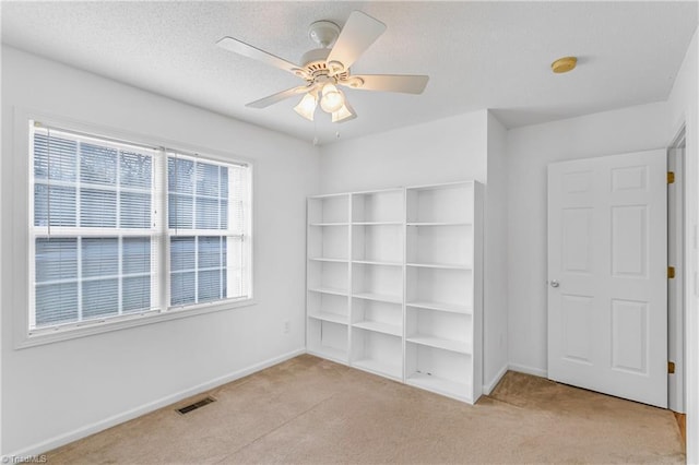 unfurnished bedroom featuring baseboards, visible vents, a textured ceiling, and light colored carpet