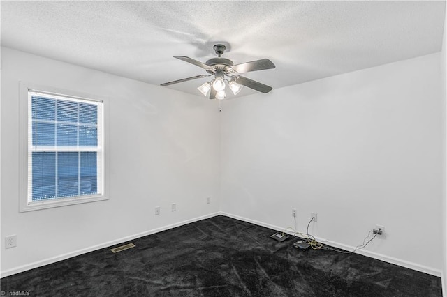 unfurnished room featuring baseboards, visible vents, ceiling fan, dark colored carpet, and a textured ceiling