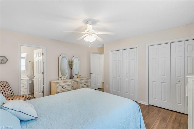 bedroom featuring baseboards, a ceiling fan, wood finished floors, ensuite bathroom, and multiple closets