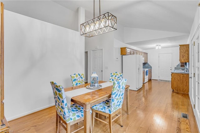 dining area featuring baseboards, vaulted ceiling, visible vents, and light wood finished floors