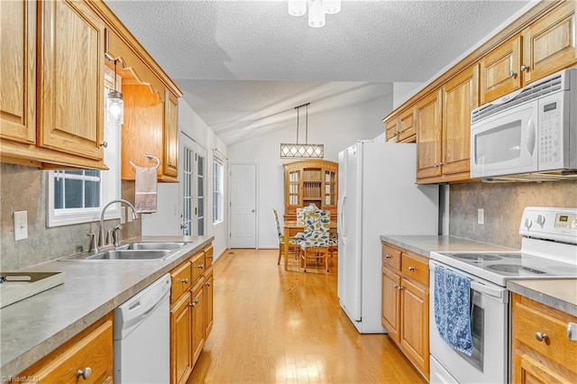 kitchen with lofted ceiling, light wood-style flooring, white appliances, a sink, and backsplash