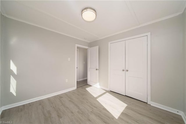 unfurnished bedroom with ornamental molding, a closet, and light wood-type flooring