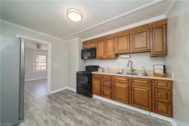 kitchen with sink, ornamental molding, black appliances, and light wood-type flooring