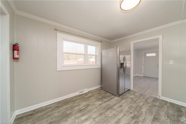 unfurnished bedroom featuring crown molding, light hardwood / wood-style flooring, and stainless steel fridge with ice dispenser