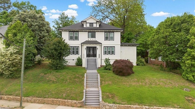american foursquare style home featuring stairs, stucco siding, and a front lawn