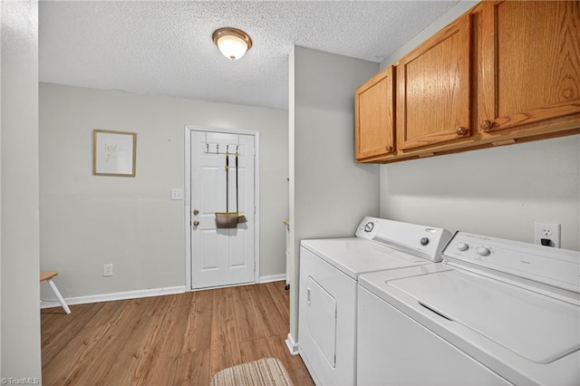209 Brewer Cir, East Bend, NC 27018 - laundry room featuring washing machine and dryer, light wood-style flooring, cabinet space, and a textured ceiling