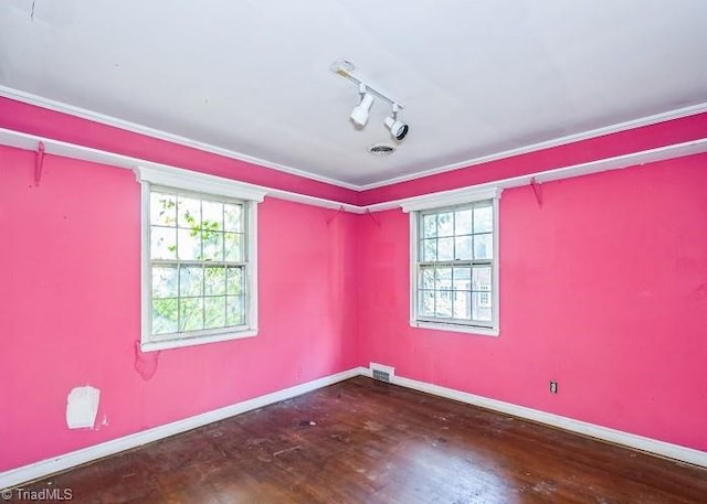 empty room featuring ornamental molding, a healthy amount of sunlight, track lighting, and hardwood / wood-style flooring