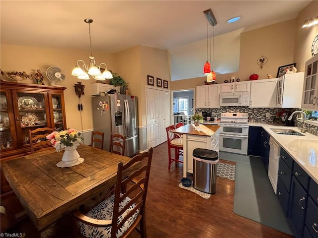 kitchen featuring decorative light fixtures, sink, white cabinets, a center island, and white appliances