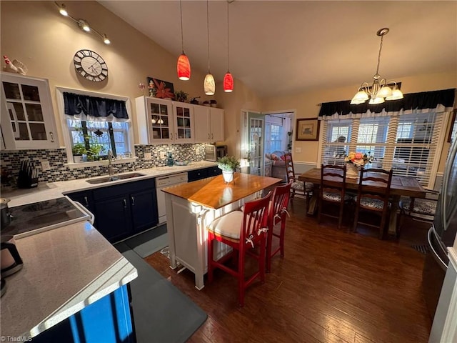 kitchen with sink, a breakfast bar, a center island, white cabinets, and decorative light fixtures