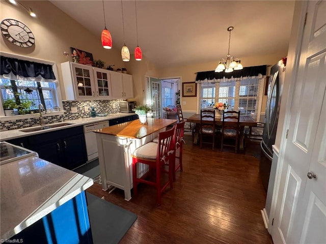 kitchen with sink, white cabinetry, a kitchen breakfast bar, white dishwasher, and a healthy amount of sunlight