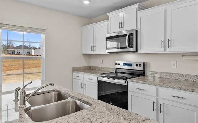 kitchen with light stone counters, recessed lighting, a sink, white cabinetry, and appliances with stainless steel finishes