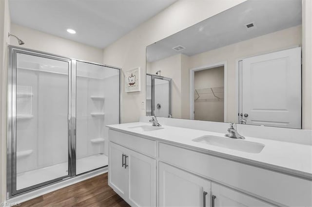 full bath with wood finished floors, a sink, visible vents, and a shower stall