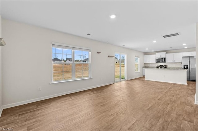 unfurnished living room featuring light wood-style floors, baseboards, visible vents, and recessed lighting