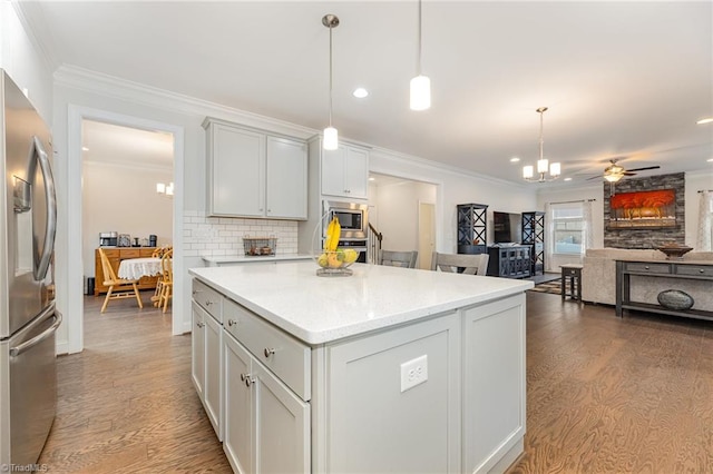 kitchen featuring light hardwood / wood-style floors, a center island, tasteful backsplash, pendant lighting, and appliances with stainless steel finishes