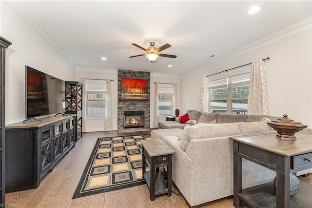 living room with hardwood / wood-style floors, a fireplace, ceiling fan, and ornamental molding