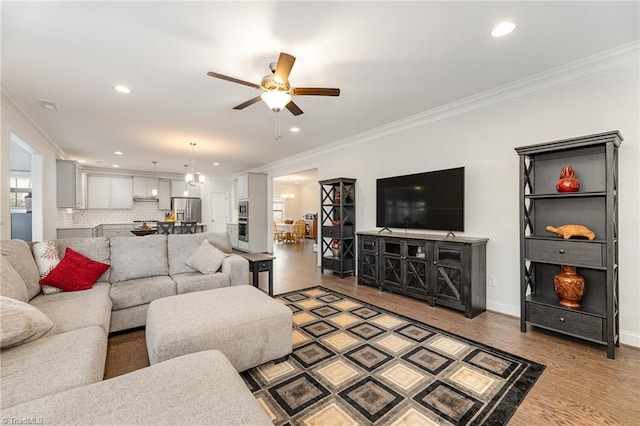 living room featuring hardwood / wood-style floors, ceiling fan, and crown molding