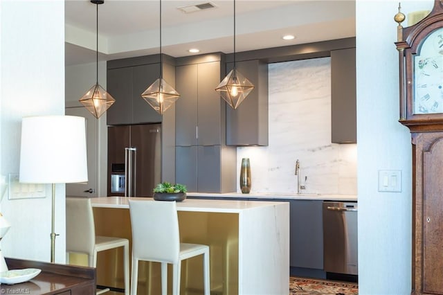 kitchen featuring sink, gray cabinets, pendant lighting, stainless steel appliances, and backsplash