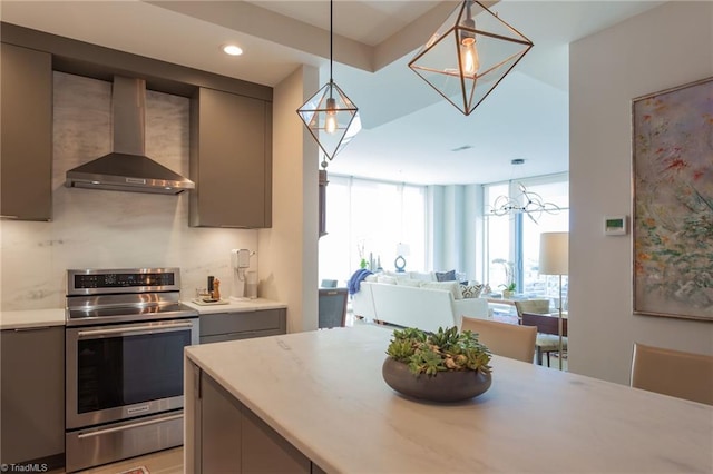 kitchen with gray cabinets, decorative light fixtures, backsplash, electric range, and wall chimney range hood