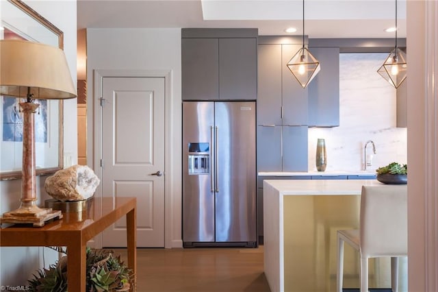 kitchen with pendant lighting, high end refrigerator, light wood-type flooring, and gray cabinetry