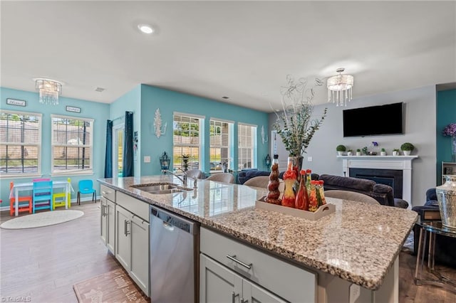 kitchen with a sink, white cabinets, open floor plan, and stainless steel dishwasher