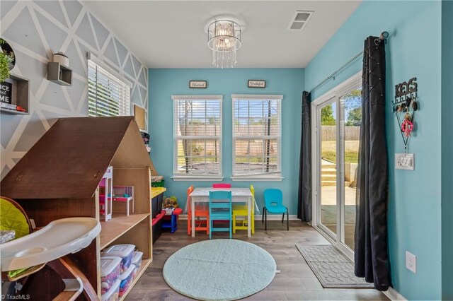 rec room with an inviting chandelier, baseboards, visible vents, and wood finished floors