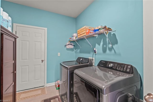 washroom featuring laundry area, light tile patterned floors, baseboards, and washing machine and clothes dryer