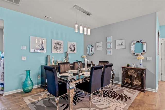 dining space featuring light wood finished floors, visible vents, and baseboards