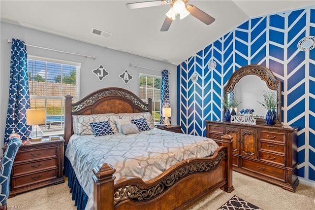 bedroom with light carpet, wallpapered walls, visible vents, an accent wall, and vaulted ceiling