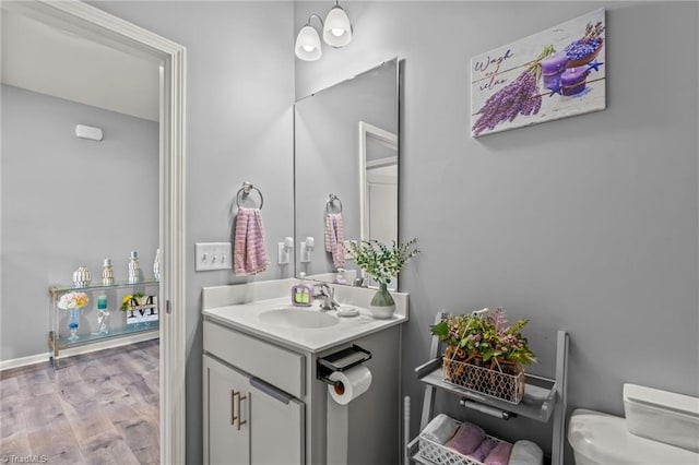 bathroom with toilet, wood finished floors, and vanity