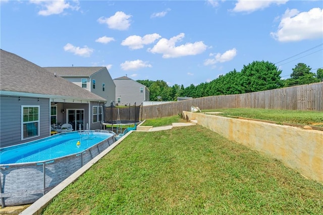 view of yard featuring a fenced backyard, a trampoline, and a fenced in pool