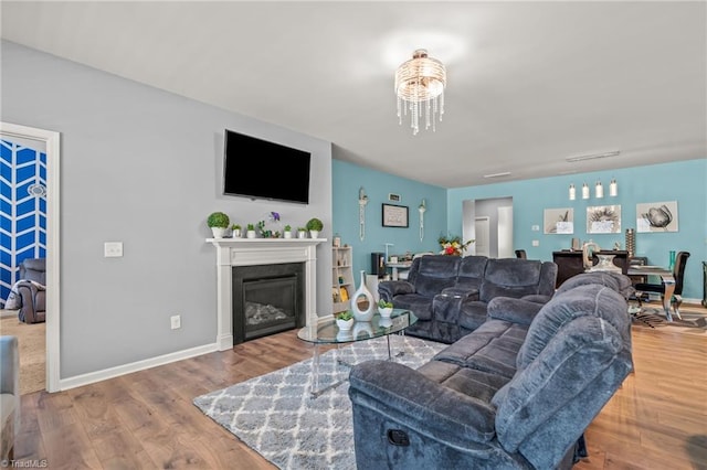 living room featuring baseboards, wood finished floors, and a glass covered fireplace