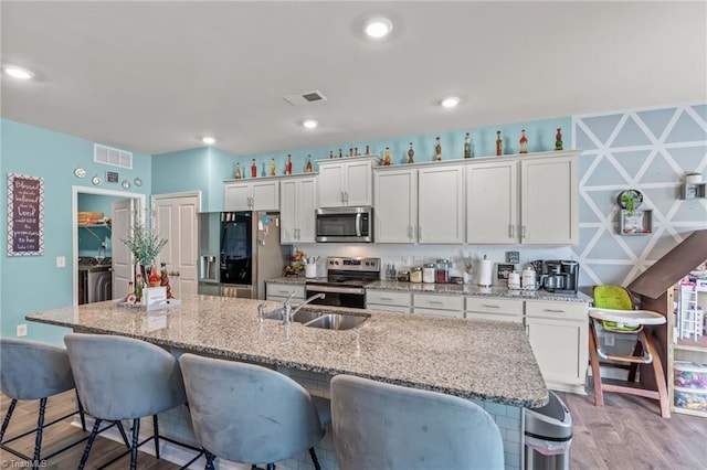 kitchen with an island with sink, white cabinetry, appliances with stainless steel finishes, and a sink